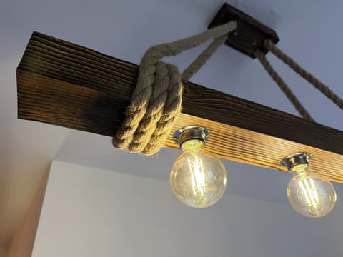 Lamp made of an old wooden beam hung on ropes with three filament bulbs