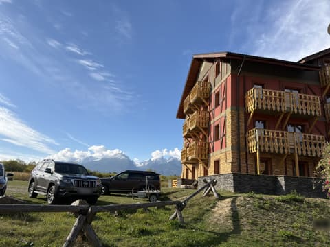 Cars parked on the grass next to the building with the High Tatras behind