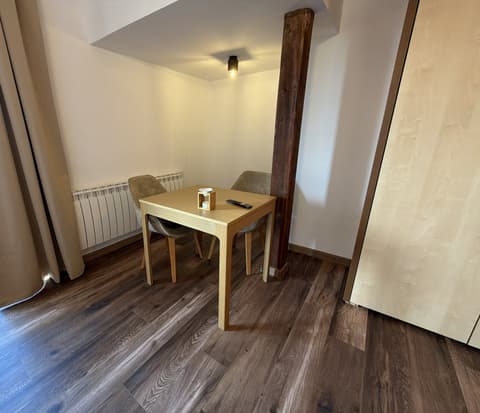 Dining table for two under a sloping ceiling next to a wooden beam