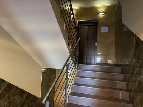 Staircase with a steel railing and the lift door on the landing